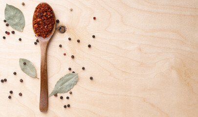 Ground chili in wooden spoon on wooden background