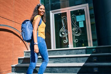 Young african american student girl smiling happy going up stairs of music academy.