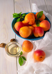 Bright orange ripe apricots in a bowl and apricot oil on a white background.