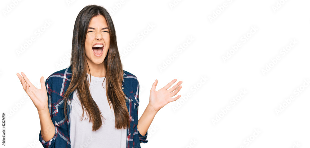 Sticker young brunette woman wearing casual clothes crazy and mad shouting and yelling with aggressive expre