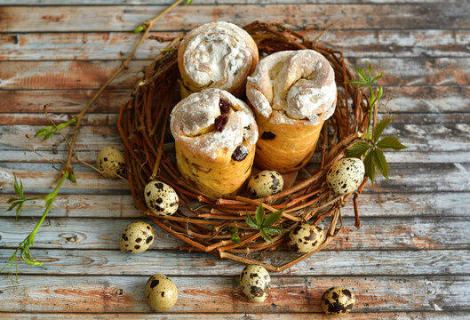 Happy easter flat lay. Easter wreath of grape branches, quail feathers and eggs on a gray wooden background. Traditional cupcake Easter, homemade kraffin with raisins,candied fruits