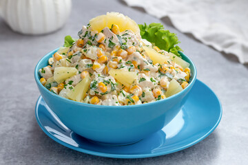Chicken salad with pineapple and corn served in a blue bowl on a light background.