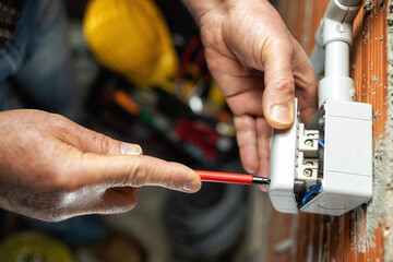 Top view. Electrician worker at work with screwdriver installs the switches of a residential...