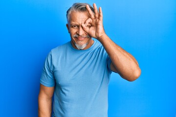 Naklejka premium Middle age grey-haired man wearing casual clothes doing ok gesture with hand smiling, eye looking through fingers with happy face.