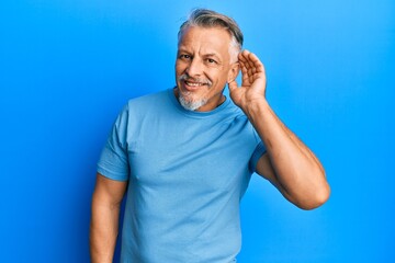 Middle age grey-haired man wearing casual clothes smiling with hand over ear listening an hearing...