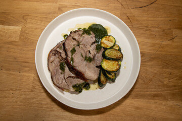 A delicious plate of Slow Roasted Lamb and Boulanger Potatoes on a wooden kitchen table