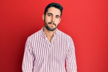Young hispanic man wearing business shirt with serious expression on face. simple and natural looking at the camera.