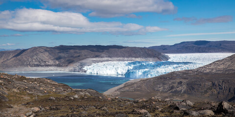 Eqi glacier in white and blue colors with floating icebergs in in blue ocean, Greenland 