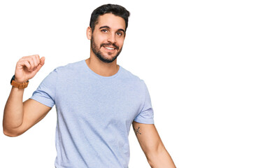 Fototapeta premium Young hispanic man wearing casual clothes dancing happy and cheerful, smiling moving casual and confident listening to music