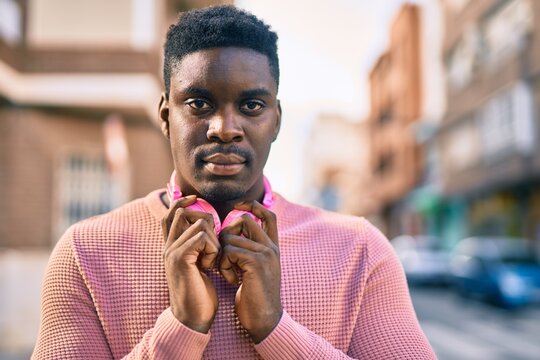 Young african american man with serious expression using headphones at the city.