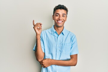 Young handsome african american man wearing casual clothes smiling happy pointing with hand and finger to the side