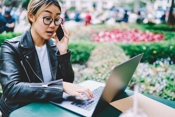 Chinese freelance copywriter working with text ideas on laptop computer and calling to remote...
