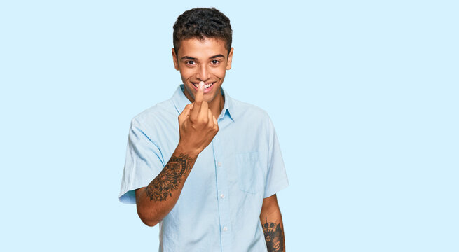 Young handsome african american man wearing casual clothes beckoning come here gesture with hand inviting welcoming happy and smiling