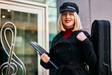 Young blonde musician woman smiling happy standing at the music academy