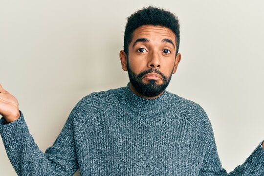Handsome hispanic man with beard wearing casual clothes clueless and confused with open arms, no idea and doubtful face.