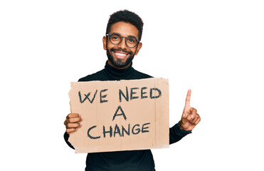 Young african american man holding we need a change banner surprised with an idea or question pointing finger with happy face, number one
