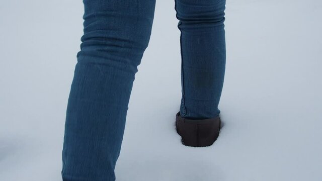 Legs walking on snow with footprints. rear view. camera follows the legs slow motion