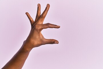 Arm and hand of black middle age woman over pink isolated background picking and taking invisible thing, holding object with fingers showing space