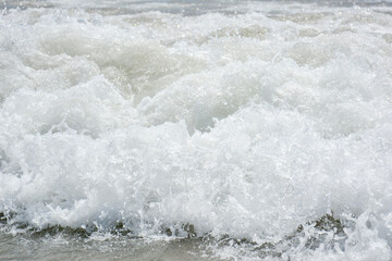 Fototapeta premium Spain L estartit, July 1 2018. Sea salty wave pours along the shore with lots of water splashes and drops and white foam rolling along the sandy shore
