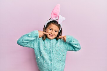 Little beautiful girl wearing cute easter bunny ears smiling cheerful showing and pointing with...