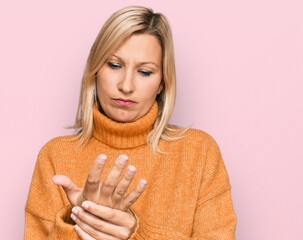 Middle age caucasian woman wearing casual winter sweater suffering pain on hands and fingers, arthritis inflammation