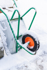 Metal garden wheelbarrow in the snow in winter