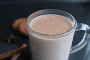 drink hot chocolate cocoa in a glass mug with cinnamon sticks and cookies on a black background with a place for text