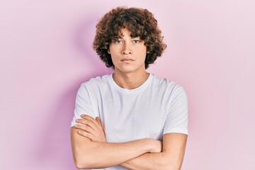 Handsome young man wearing casual white t shirt skeptic and nervous, disapproving expression on face with crossed arms. negative person.