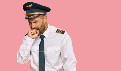 Handsome man with beard wearing airplane pilot uniform feeling unwell and coughing as symptom for cold or bronchitis. health care concept.