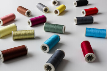 The spools of colorful thread on the white background. Selective focus.