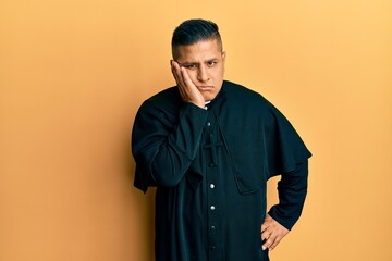 Obraz premium Young latin priest man standing over yellow background thinking looking tired and bored with depression problems with crossed arms.
