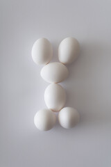 White Easter eggs stacked on top of each other against white background. Natural minimal composition on daylight. Organic food lay out.