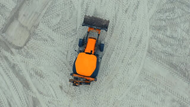 Backhoe loader works at a construction site, removing soil. Aerial top down view