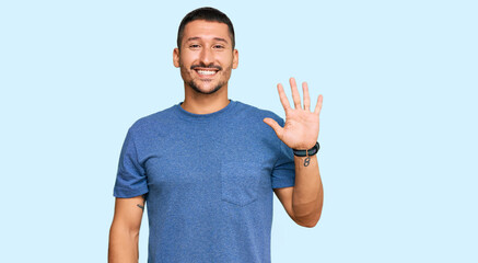 Naklejka premium Handsome man with tattoos wearing casual clothes showing and pointing up with fingers number five while smiling confident and happy.
