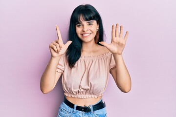 Young hispanic girl wearing casual clothes showing and pointing up with fingers number seven while smiling confident and happy.