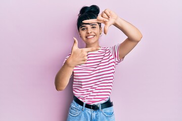 Obraz na płótnie Canvas Young hispanic girl wearing casual clothes smiling making frame with hands and fingers with happy face. creativity and photography concept.