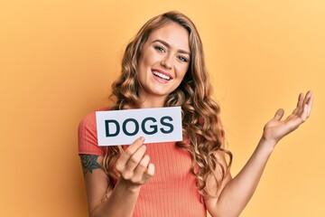 Young blonde girl holding paper with dogs message celebrating achievement with happy smile and winner expression with raised hand