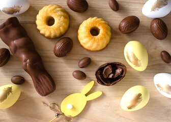 Yellow Easter and Chocolate Eggs, Easter Decor and cakes on wooden background. Easter concept in pastel yellow. Close-up. Top  view.