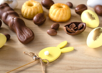 Easter Decor, Pastel Yellow and Chocolate Eggs, rabbit and cakes  on wooden background.  Top view