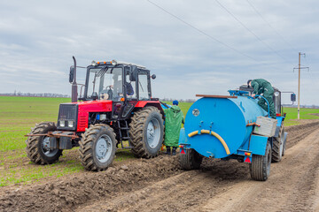 Obraz premium An agricultural tractor is filled with pesticides for further application to the soil. Spraying and fertilizing the soil. Feeding plants with pesticides.