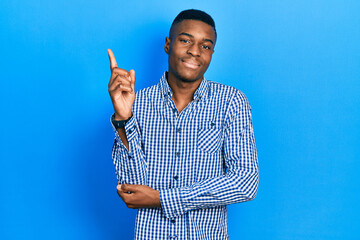 Young african american man wearing casual clothes with a big smile on face, pointing with hand and...