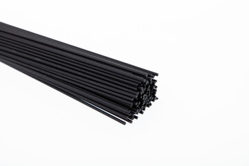 Bunch of uncooked black spaghetti pasta isolated on white
