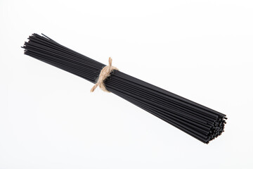 Bunch of uncooked black spaghetti pasta isolated on white