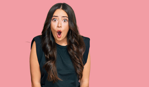 Beautiful brunette young woman wearing black shirt afraid and shocked with surprise expression, fear and excited face.