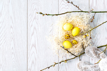 Colorful yellow chicken and quail easter eggs with bunny toy, nest and willow branches, spring, easter concept
