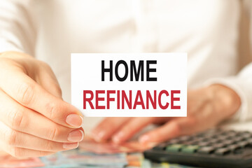 a woman in a white shirt holds a piece of paper with the text: home refinance, business concept.