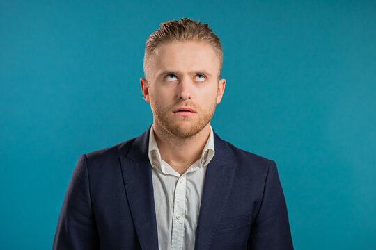 Irritated Businessman Sighs, Rolling Eyes On Blue Background. European Guy In Displeasure, He Is Tired Of Situation, Thinks How Cant You Still Not Understand. 