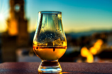 Expensive single malt whiskey in the rays of the setting sun, in the background a picturesque Spanish town with a church tower