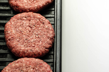 Seasoned beef burgers with a pinch of salt and black pepper on the grill