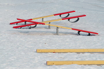 Baby seesaws outside on playground with crumbly melting spring snow